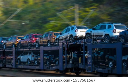 Transportation of cars by train. Autorack with cars. New cars transported with railway platforms. Panning effect. No logo or brand. SUV  Royalty-Free Stock Photo #1539581567
