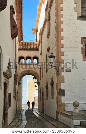 Narrow street between the Museum Maricel de Mar and Palace Maricel during sunrise. Town of Sitges, province of Barcelona, Catalonia, Spain.