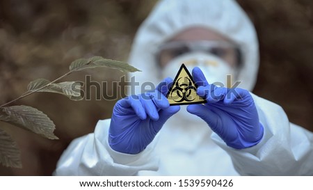 Biological hazard sign in researcher hands, health threat, virus danger, toxin Royalty-Free Stock Photo #1539590426