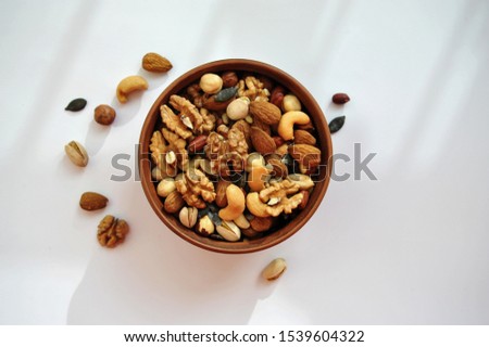 clay plate with nuts on a white background Royalty-Free Stock Photo #1539604322