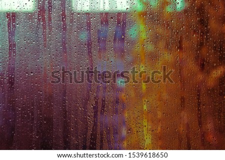 Closeup picture of rain drops flowing down the window in autumn