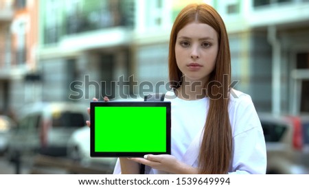 Serious girl holding green screen tablet, online courses, free trial lesson