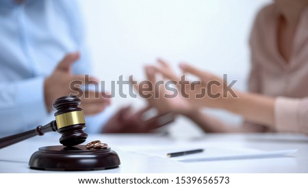Spouses arguing about property division during divorce, gavel and rings closeup Royalty-Free Stock Photo #1539656573