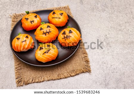 Funny Halloween Sushi Pumpkins Jack o Lantern, Sushi Monsters. Temari sushi, sushi balls. Healthy food for kids. Ceramic plate, sackcloth, stone concrete background, copy space, close up