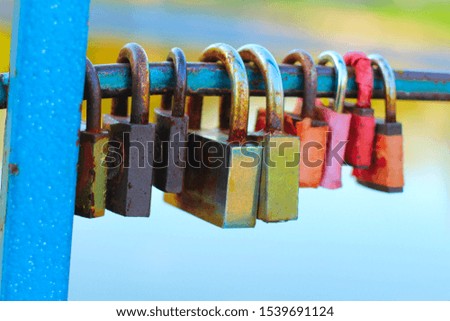 colored padlocks on the railing of the bridge over the river