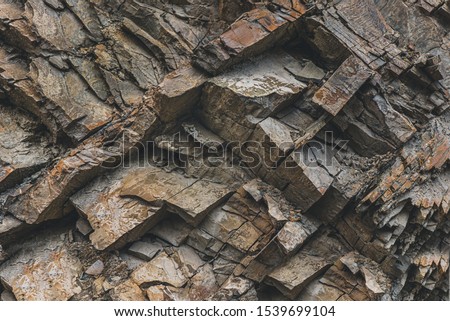 Layers and cracks in sedimentary rock on cliff face, background. Cliff of rock mountain. Rock slate in the mountain. Cracks and layers of sandstone. Royalty-Free Stock Photo #1539699104