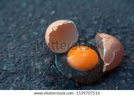 Broken egg on asphalt as a symbol of failure, negative experience, destruction, death