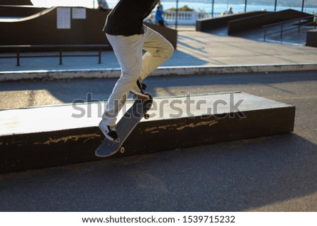 Young guy performs a tricks on skateboard in a city skate park. Skateboarder jumping and sliding on the grind box. Extreme sports is very popular among youth.