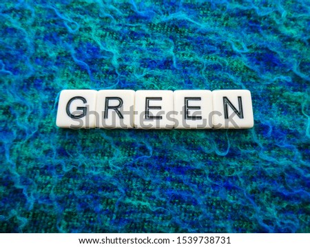 Woven textured green and blue colored background sign with the word "GREEN" in text lettering, for a vivid and eye catching sign, banner, graphic, poster or placard