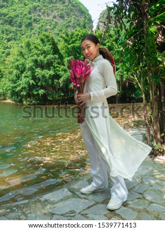Asian woman in aodai with lotus at the lake