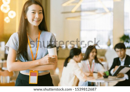 close up smart attractive asian business female smile hand hold hot drink with modern office background