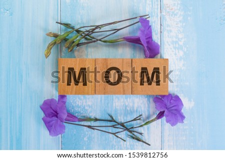 Wooden cube block mom word with purple flower on rustic blue background