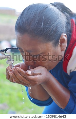 Native american woman drinking water from faucet.