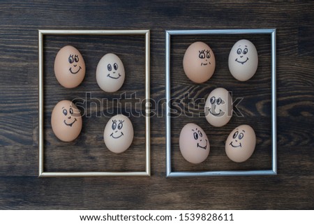 Picture golden frame and many funny eggs smiling on dark wooden wall background, close up. Eggs family emotion face portrait. Concept funny food