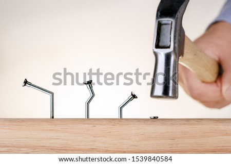 Learning from mistakes Businessman  hammering nails. Goal achievement. Royalty-Free Stock Photo #1539840584