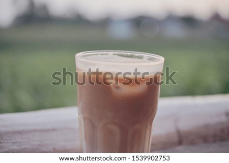 close up of ice cappuccino with green field as a background