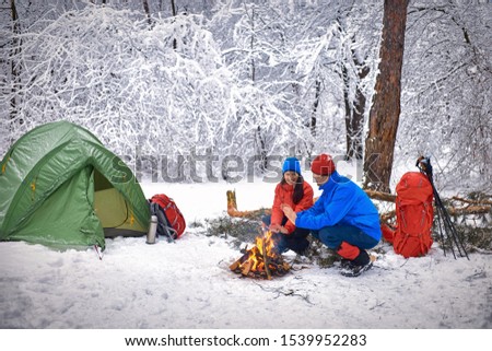 Camping in the winter forest of a couple in love. Royalty-Free Stock Photo #1539952283