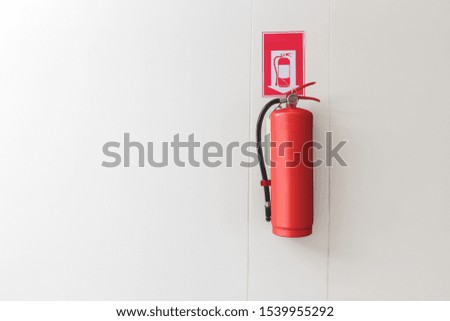 Red Fire extinguisher on the white wall background.
