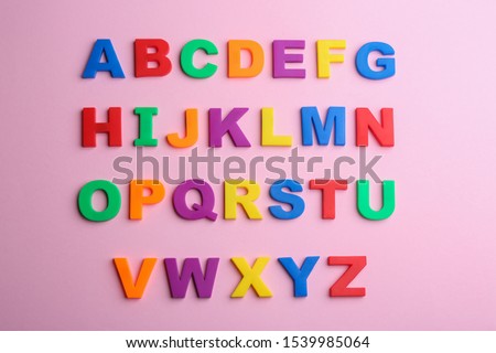 Colorful magnetic letters on pink background, flat lay. Alphabetical order