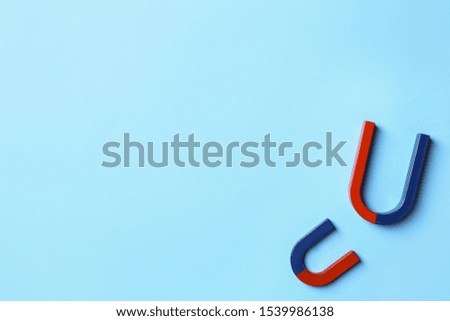 Horseshoe magnets on light blue background, flat lay. Space for text