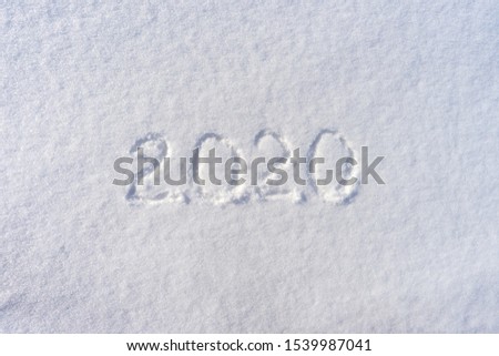 Text 2020 written on white fresh snow in sunny winter day. Merry Christmas and Happy New Year. Winter holiday concept.