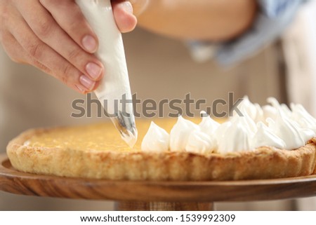 Woman preparing lemon meringue pie, closeup view