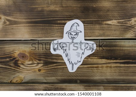 Drawing paper sketch of evil scarecrow on wooden background