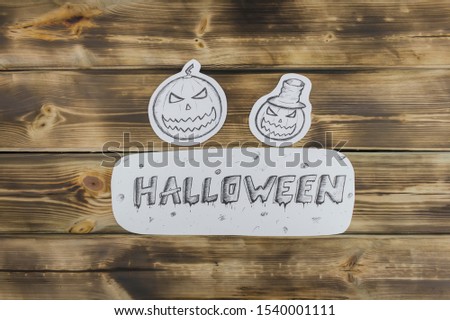 Drawing paper sketch of evil pumpkins on wooden background