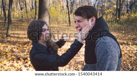 A woman slaps a man in the face. An emotional male is getting slapped in face, crouching his face with closed eyes in a fear. Royalty-Free Stock Photo #1540043414