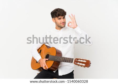 Young handsome man with guitar over isolated white background showing ok sign with fingers