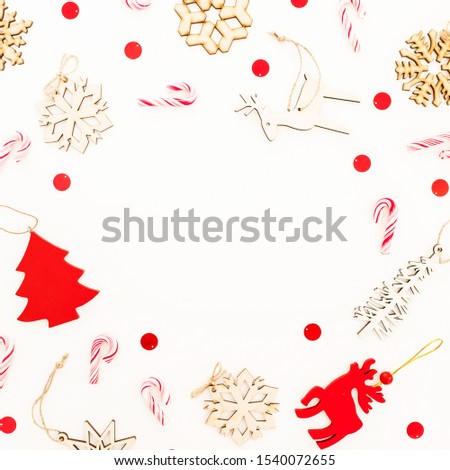 Christmas frame with wooden decoration, snowflakes and candy canes on white. Flat lay, top view.