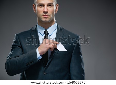 Portrait of man who pulls out white card from the pocket of business suit, copyspace