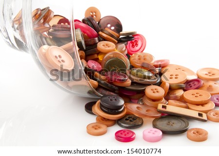 Buttons in a glass on its side on a white background