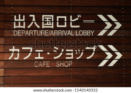 White paint sign on wood wall. Japanese text is Departure lobby and cafe shop.