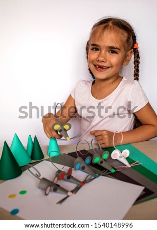 Cute little 7-8 years old girl making crafted  mice with colored paper and decorative punchers, color paper to create fun and easy with children, concept for kindergarten, 2020 year animal symbol