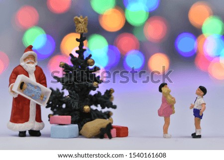 Miniature Santa Claus is giving a kid a present fot the chrsitmas tree