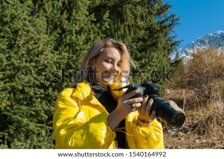 Young blond girl with photo camera outdoors. Autumn conception. Yellow trees background