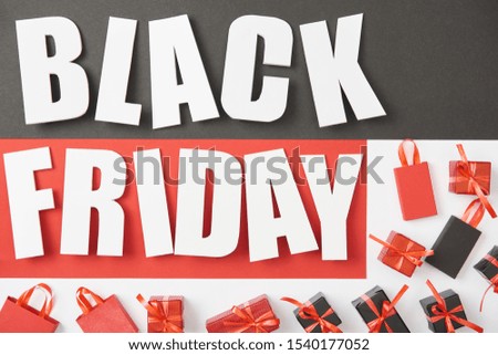 top view of black friday lettering near presents on black, red and white background