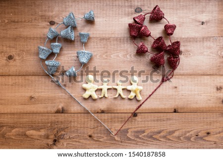 The image of a loving family. Figures of people from the dough framed by shiny jewelry on a wooden background. Valentine's Day. Selective focus. Place for text.