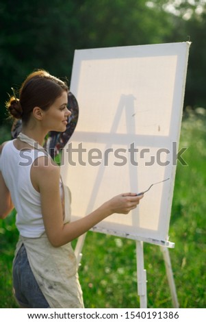 stylish young easel woman on nature with brush