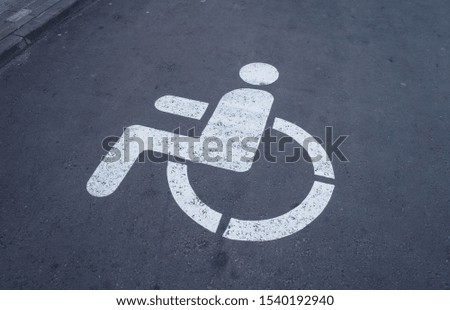 Disabled parking sign on asphalt road.