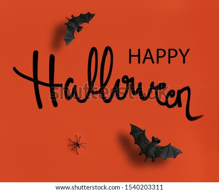 Happy Halloween text on orange background with bats and spider