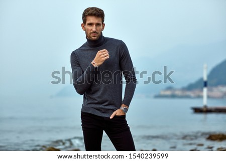 Handsome man in autumn outfit relaxing on the beach 