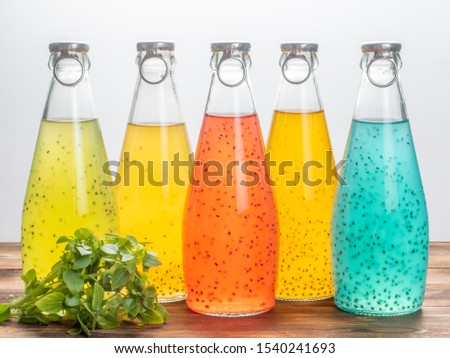 Five bottles of Basil Seed on a white background with basil leaves. Red, yellow, light blue and green color. Soft focus. Royalty-Free Stock Photo #1540241693