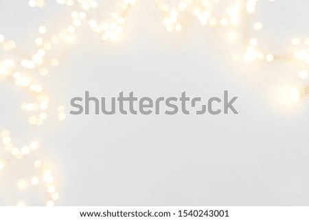 Border of defocused Christmas lights on white wooden background. Christmas and New Year holidays celebration concept