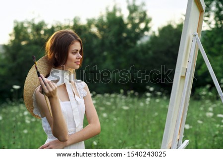 young woman holding brush for painting on canvas