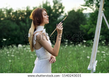 young woman holding brush for painting on canvas