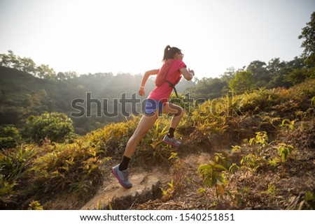 Woman ultramarathon runner running up on mountain slope in tropical rainforest Royalty-Free Stock Photo #1540251851