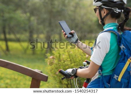 Woman using smartphone while riding bike on sunny day in park