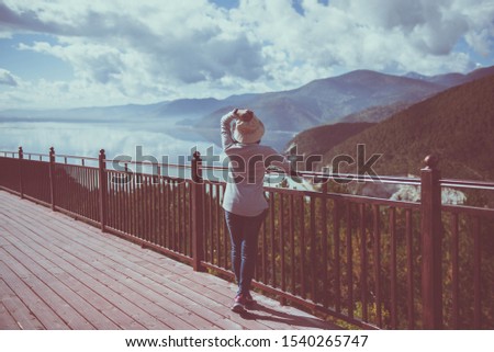 Happy and cheering woman standing and looking beautiful view while looking amazing mountains views at outdoor